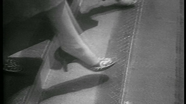 1953年B/W close up feet of two women in high heels walking down outside /新闻片视频素材