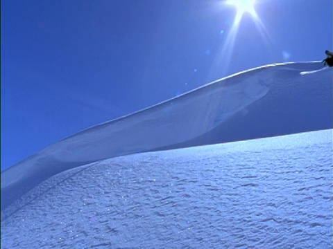 慢动作低角度滑雪板做跳下斜坡/太阳背景视频下载