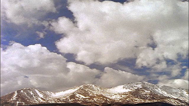 宽镜头时间间隔白色蓬松的云在蓝天上白雪覆盖的瓦萨奇山/圣丹斯，犹他州视频素材