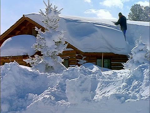 有人站在小屋屋顶上铲雪视频素材