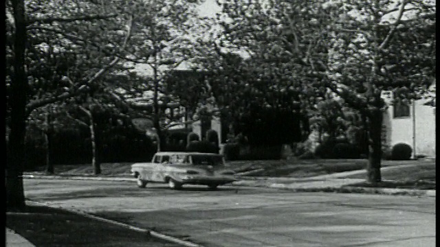 1959年PAN旅行车驶离路边，沿着郊区街道行驶视频素材