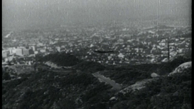 1952年，一名PAN男子带着喷气背包飞过群山，城市为背景视频素材