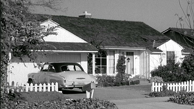 1951年一对夫妇带着孩子开着雪佛兰汽车驶入郊区住宅的车道视频素材