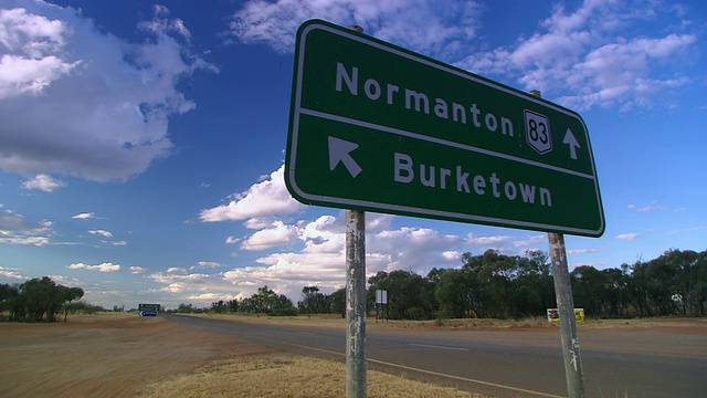 WS Burke镇道路标志&汽车行驶在多云的天空/ Cloncurry，昆士兰，澳大利亚视频素材