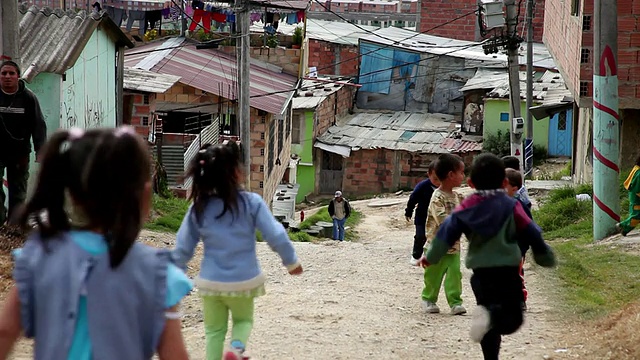 在哥伦比亚波哥大的Ciudad Bolivar贫民窟泥泞的街道上奔跑和玩耍的蹒跚学步的孩子视频素材