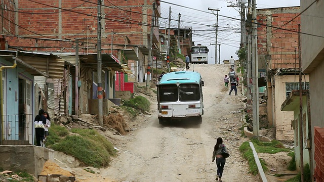 哥伦比亚波哥大Ciudad Bolivar贫民窟尘土飞扬的街道上的行人和车辆视频素材