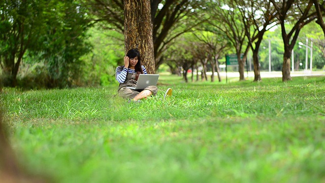 亚洲女人在公园里用笔记本电脑视频素材