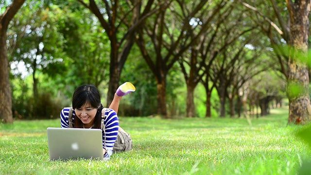 亚洲女人在公园里用笔记本电脑视频素材