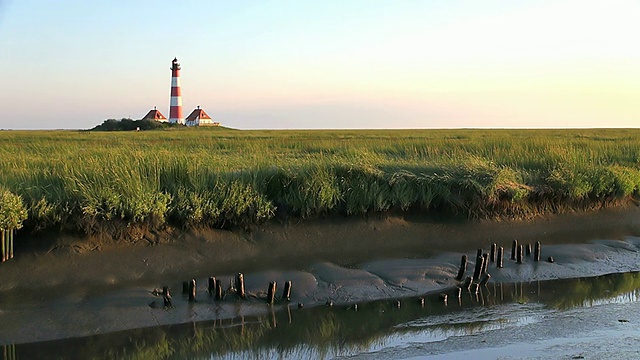 从干涸的河流和绿色的草地上观看Westerhever灯塔/ Westerhever，石勒苏益格荷尔斯泰因，德国视频素材