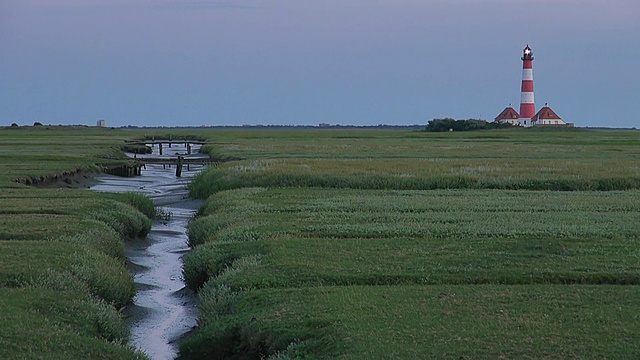 日落时从草地和流动的河流小径眺望Westerhever灯塔，北弗里斯兰瓦登海/ Westerhever，石勒苏益格荷尔斯泰因，德国视频素材