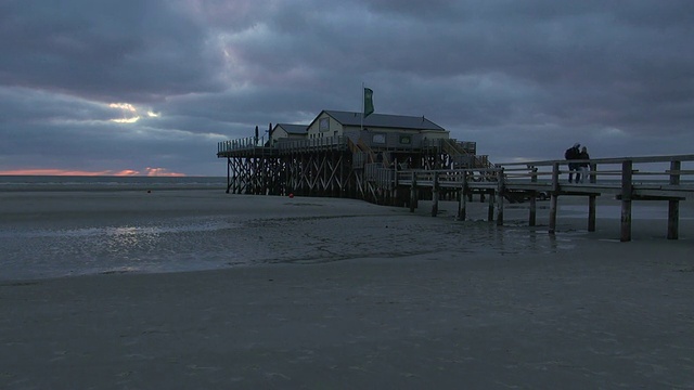 在北海北弗里斯兰，/ St. Peter Ording，石勒苏益格荷尔斯泰因，德国，日落时，海滩边cafÃ©的WS视图视频素材