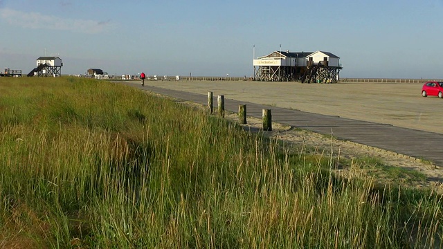 从北海北弗里斯兰/ St. Peter Ording，石勒苏益格荷尔斯泰因，德国，沿着草地的海滩边的餐厅cafÃ©的WS视图视频素材