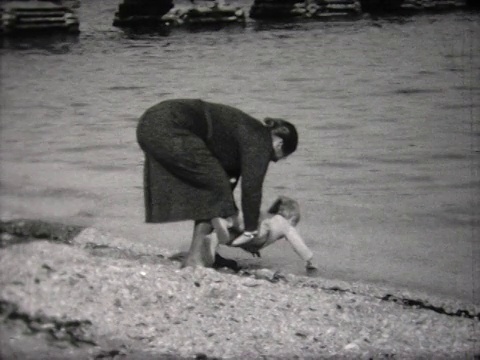 1932年，一个小男孩和看守人在海滩上视频素材