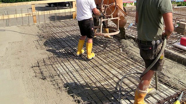 德国，莱茵兰-普法尔茨，Hermeskeil建筑工地上，工人从水泥桶里洒水泥视频素材