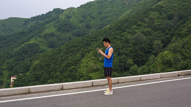 一个年轻人在森林公路上跑步后正在休息视频素材