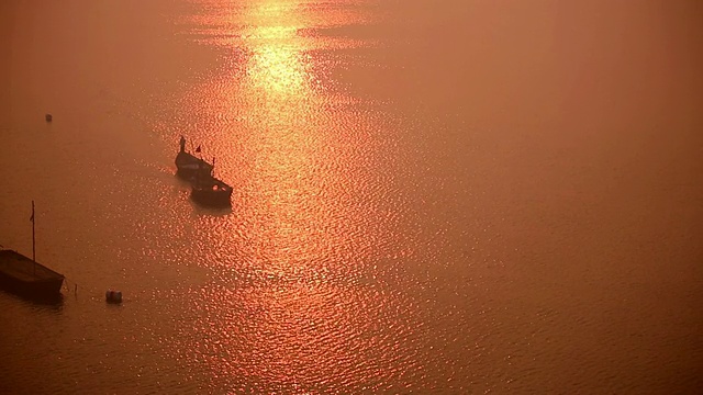 两艘船在宽阔的河面上缓慢地移动着，夕阳的余辉像铜一样闪闪发光。印度视频素材