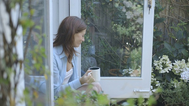 在外面喝咖啡的女人抚摸着猫。视频素材