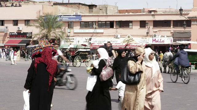 这张照片拍摄于摩洛哥马拉喀什Djemaa El Fnaa大街上，人们推着一辆马车行走视频素材