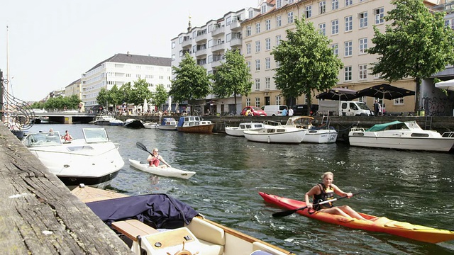 在丹麦哥本哈根的nyhavn运河上的船只和皮艇，人们和建筑视频素材