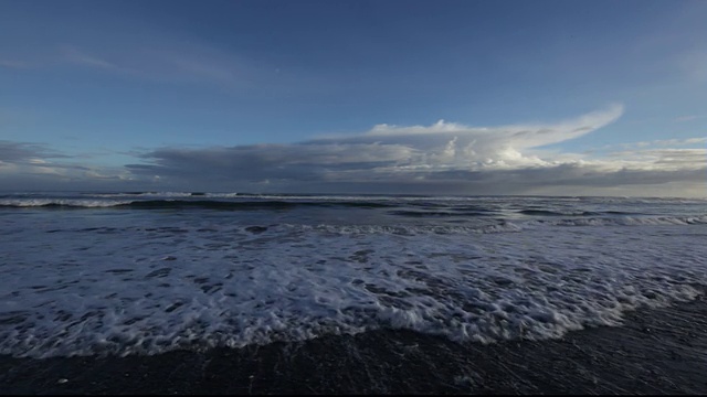 穆迪海岸波浪翻滚到黑色的沙滩。视频素材