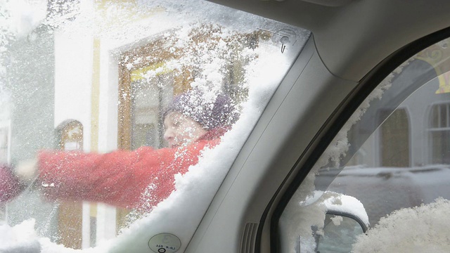 一个女人从车窗里刮雪和冰视频素材