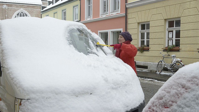 一个女人从车窗里刮雪和冰视频素材