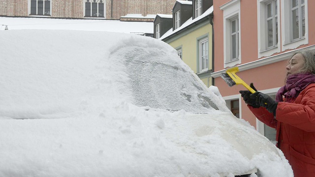 一个女人从车窗里刮雪和冰视频素材