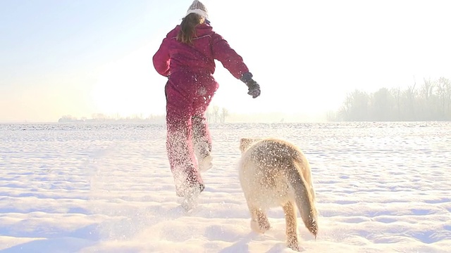 慢动作女孩和一只小狗在雪中奔跑视频素材