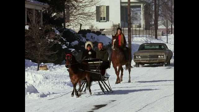 1970年代家庭电影-夫妇在下雪的街道上骑雪橇视频素材