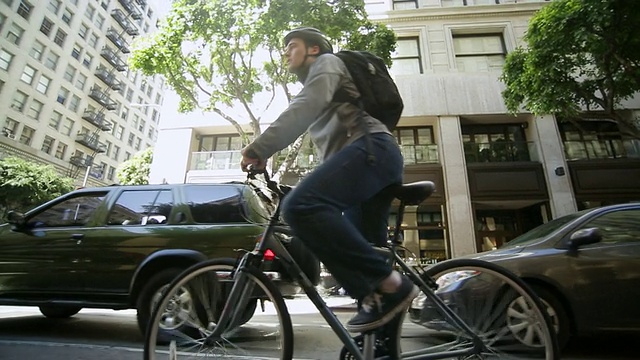 年轻人骑着自行车，回望着城市的街道视频下载