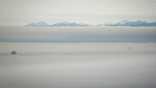 在冬季的白天，两艘渡船在浓雾中时隐时现，以奥林匹克山脉为背景视频素材