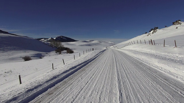 POV的雪覆盖的道路通过雪覆盖草原沿着山脉景观。视频素材