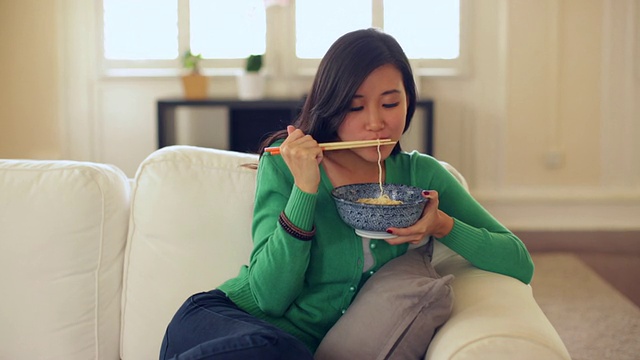 年轻女子在家吃面条。视频素材