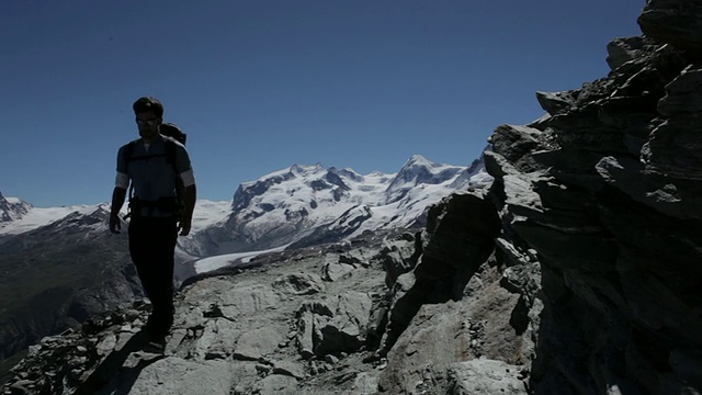 登山者在欧洲阿尔卑斯山的岩石悬崖上行走视频素材