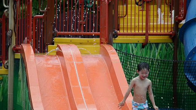 亚洲小孩从水滑梯上滑下来。视频素材