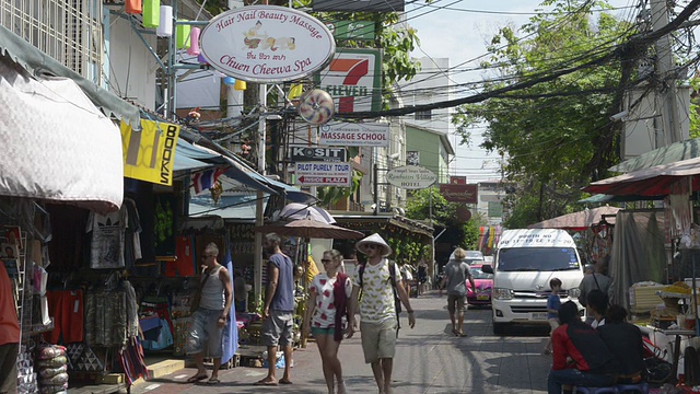 在曼谷旅游区，游客走在商店林立的街道上视频素材