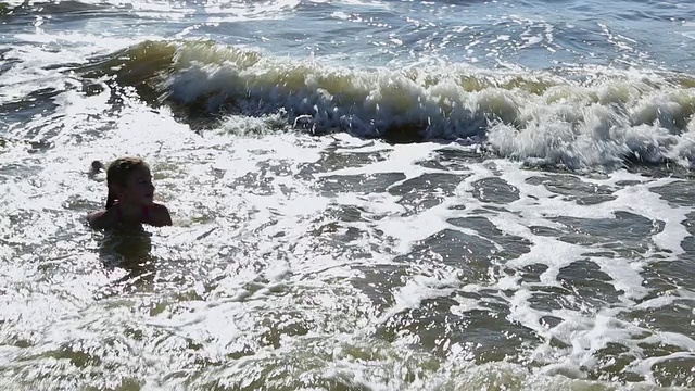 小女孩在海浪中玩耍和游泳的照片/圣西蒙斯岛，乔治亚州，美国视频素材