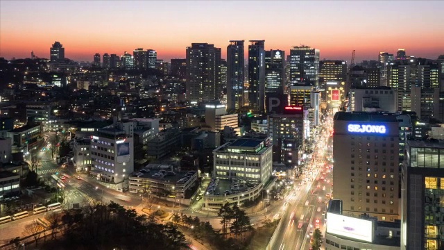 明洞的夜景，摩天大楼和来往的车辆视频素材