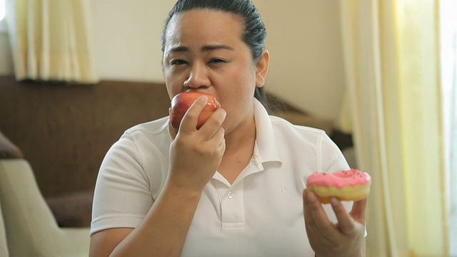 胖女人选择一个甜甜圈或苹果视频素材