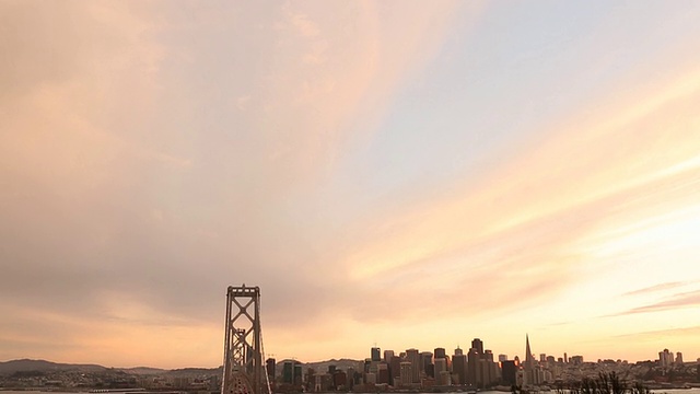 汽车和公共汽车在海湾大桥上行驶，夕阳在大桥后面。视频素材