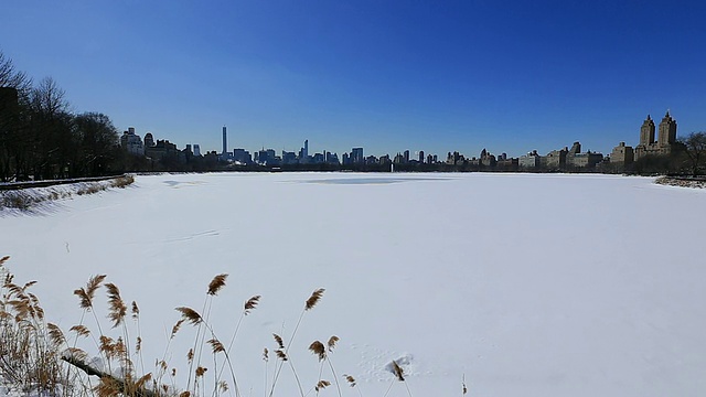 PAN摄像机捕捉到了冰冻的水库和曼哈顿摩天大楼。水库因低温被雪覆盖而完全冻结。视频素材