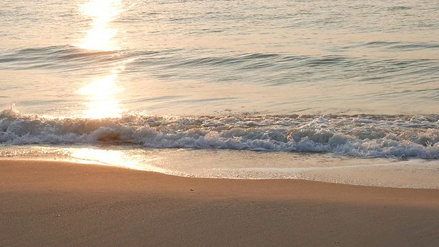 随着日出，海浪拍打在海滩上视频素材