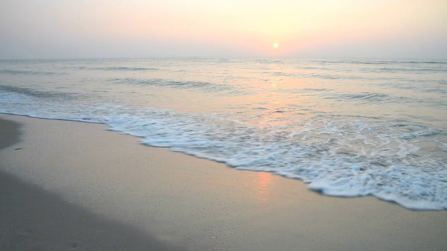 随着日出，海浪拍打在海滩上视频素材