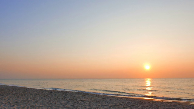 随着日出，海浪拍打在海滩上视频素材