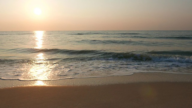 随着日出，海浪拍打在海滩上视频素材