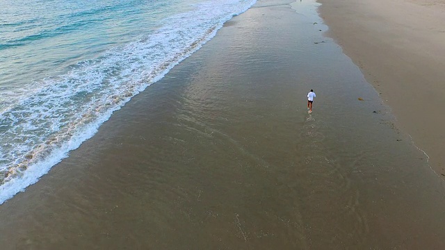 航拍的年轻人在海滩上跑步。视频素材