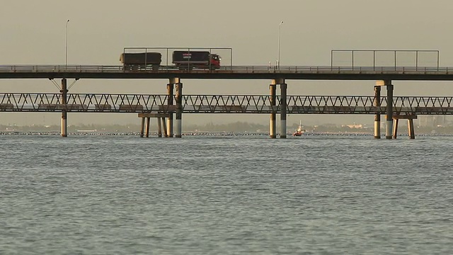 带拖车的卡车在海上桥上行驶。视频素材