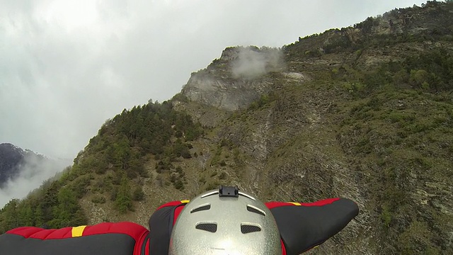 穿着飞行服的飞行员在暴风雨天气下从山顶降落视频素材