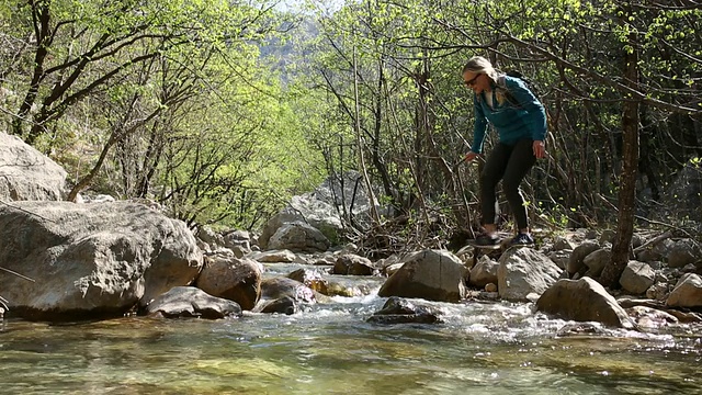 女人在春天穿过山涧，森林视频素材