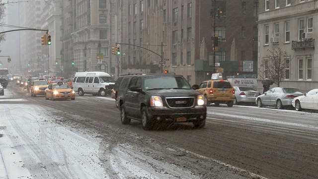 在一个大雪纷飞的冬日，纽约市中央公园外的中央公园西大街上，车辆在行驶。视频素材